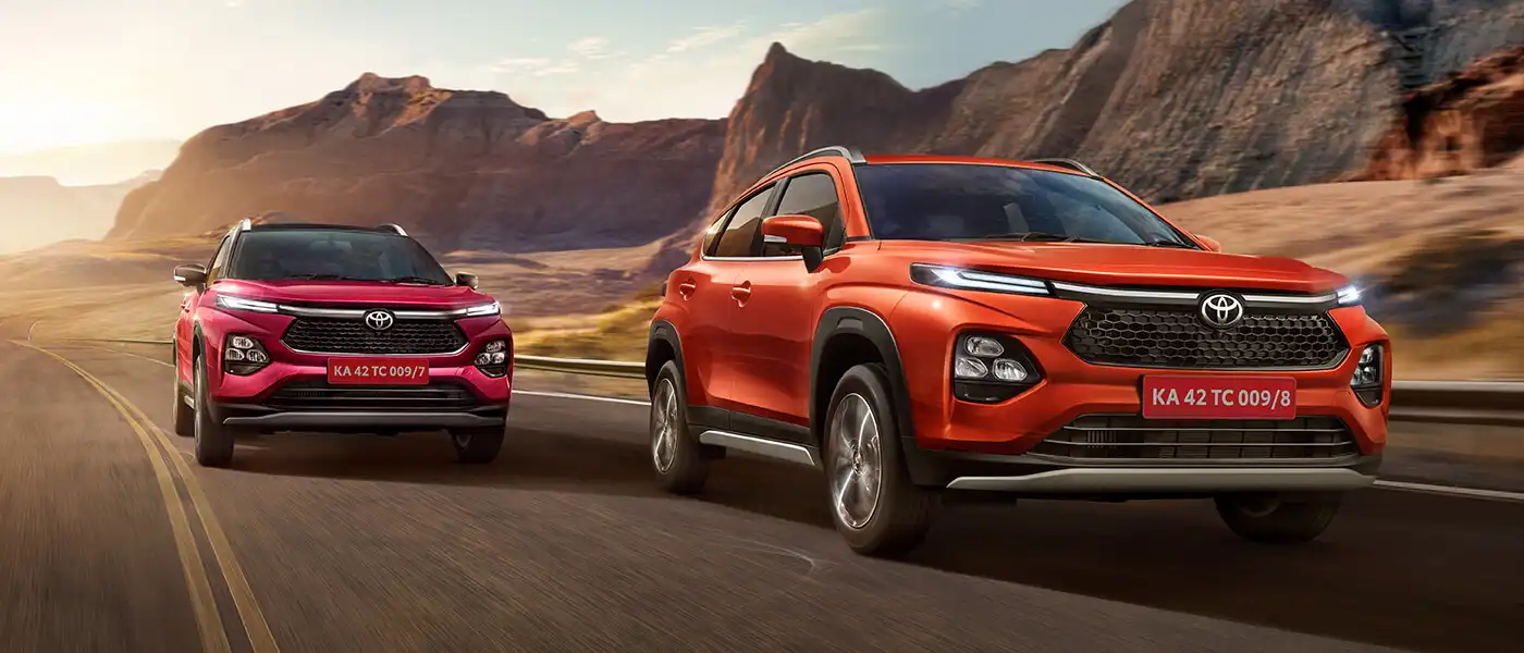 Two Toyota Urban Cruiser Taisors on a coastal mountain road at sunrise